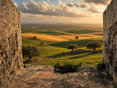 Blick durch alte Mauern auf grüne Felder – Leinwandbild